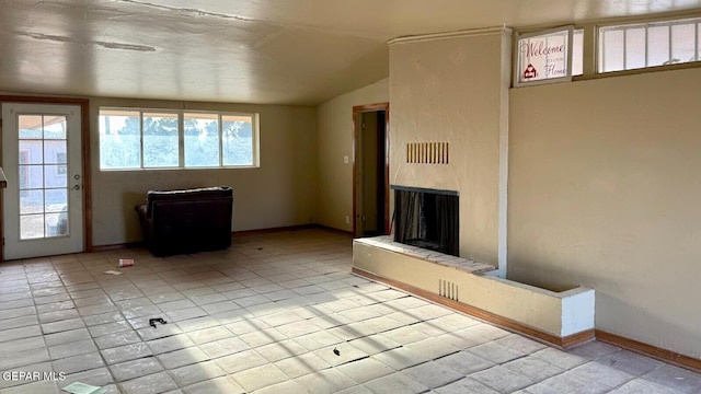 unfurnished living room featuring vaulted ceiling, a fireplace, and baseboards