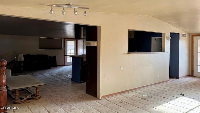 unfurnished room with vaulted ceiling, visible vents, and baseboards