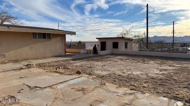 exterior space with stucco siding, an outdoor structure, and fence