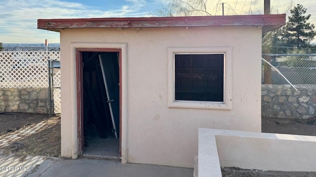 view of exterior entry with stucco siding and fence