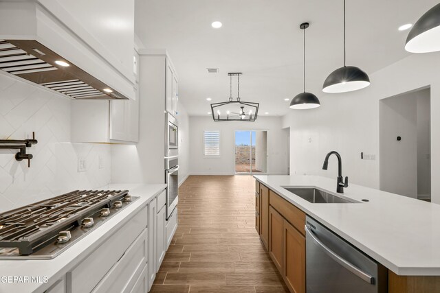 kitchen featuring tasteful backsplash, light countertops, appliances with stainless steel finishes, custom exhaust hood, and a sink