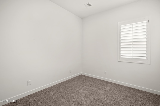 empty room featuring carpet flooring, visible vents, and baseboards