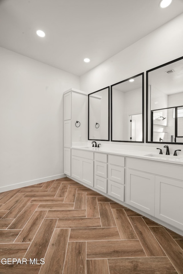 full bath with a sink, baseboards, recessed lighting, and double vanity