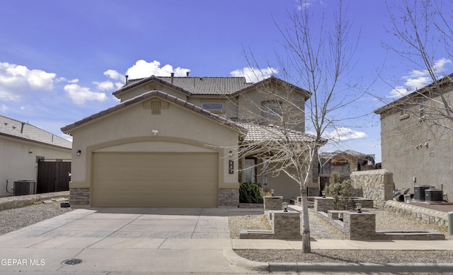 mediterranean / spanish-style house featuring central air condition unit, a tile roof, concrete driveway, stucco siding, and an attached garage