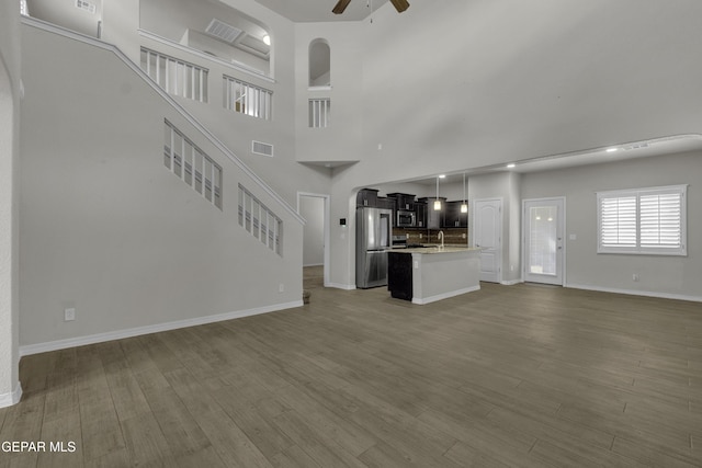 unfurnished living room with a sink, wood finished floors, baseboards, and ceiling fan