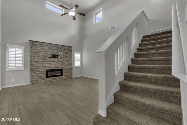 interior space with a wealth of natural light, a stone fireplace, visible vents, and wood finished floors