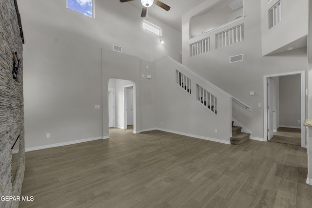 unfurnished living room featuring visible vents, arched walkways, wood finished floors, and a ceiling fan