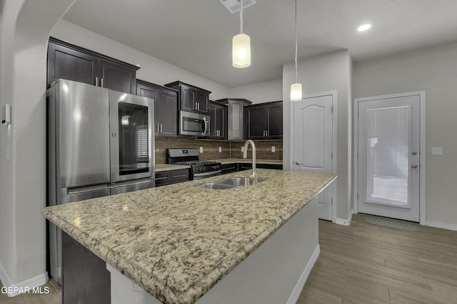 kitchen with visible vents, a sink, stainless steel appliances, pendant lighting, and tasteful backsplash