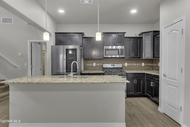 kitchen featuring visible vents, light wood-style flooring, a sink, stainless steel appliances, and tasteful backsplash