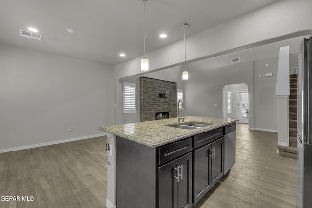 kitchen with arched walkways, visible vents, light wood-style flooring, and a sink