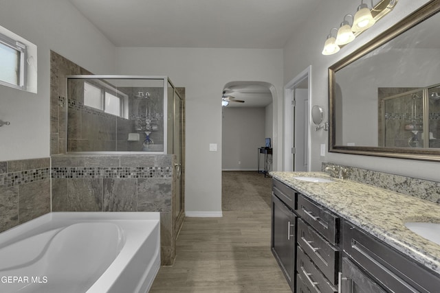 bathroom featuring baseboards, double vanity, a sink, a shower stall, and a bath