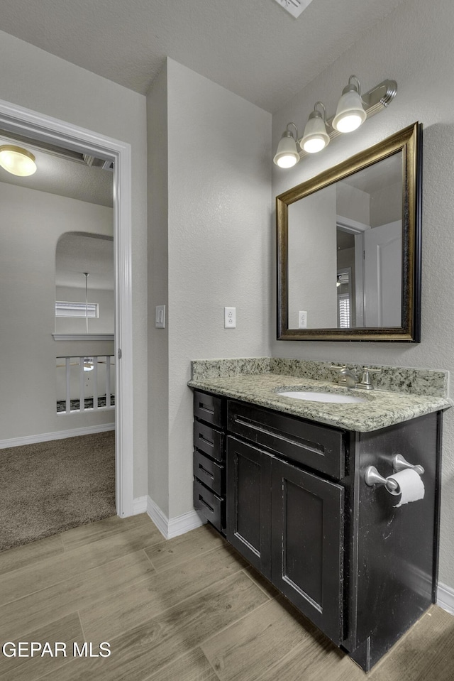 bathroom featuring vanity, baseboards, and wood finished floors