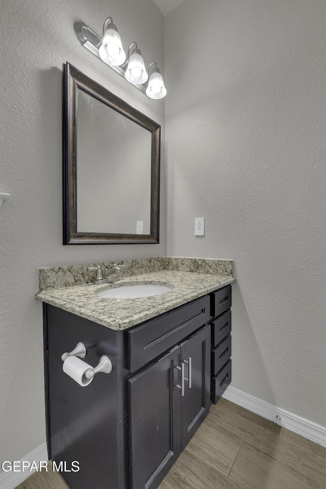 bathroom with vanity, baseboards, and wood finished floors