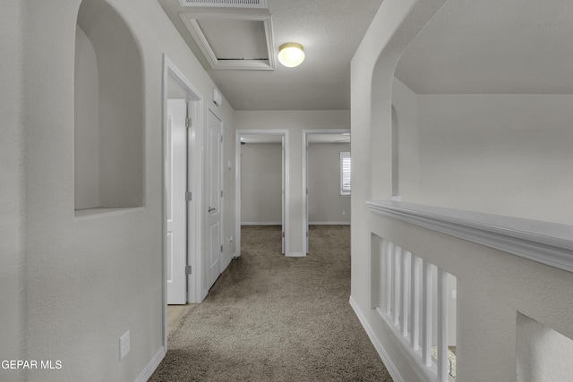 hallway featuring visible vents, carpet, baseboards, and arched walkways