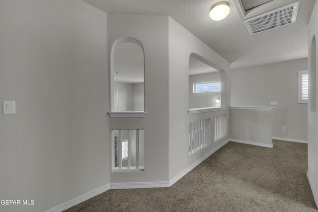 carpeted spare room with visible vents and baseboards