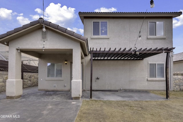 rear view of property with stucco siding, a tile roof, a pergola, and a patio area