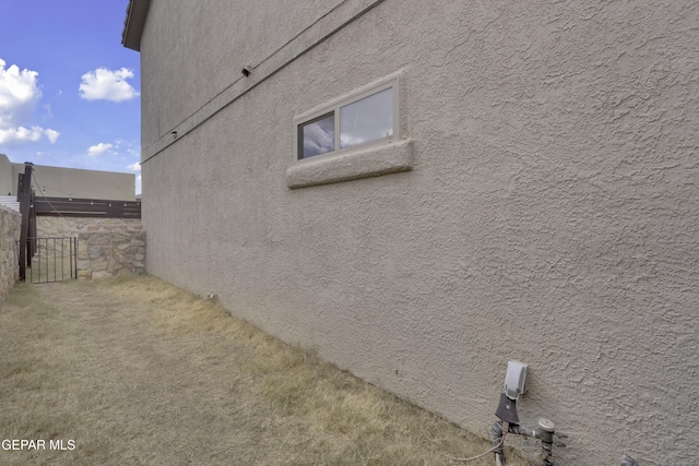 view of home's exterior with stucco siding and fence