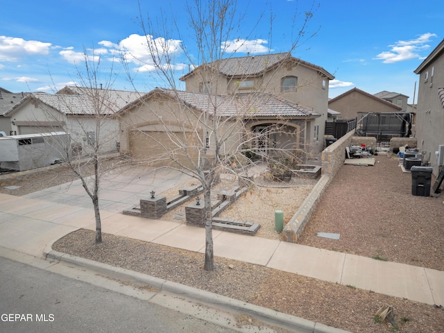 view of front of property featuring stucco siding, fence, concrete driveway, and a tile roof