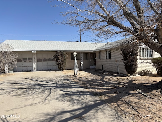 ranch-style house featuring an attached garage, brick siding, and driveway