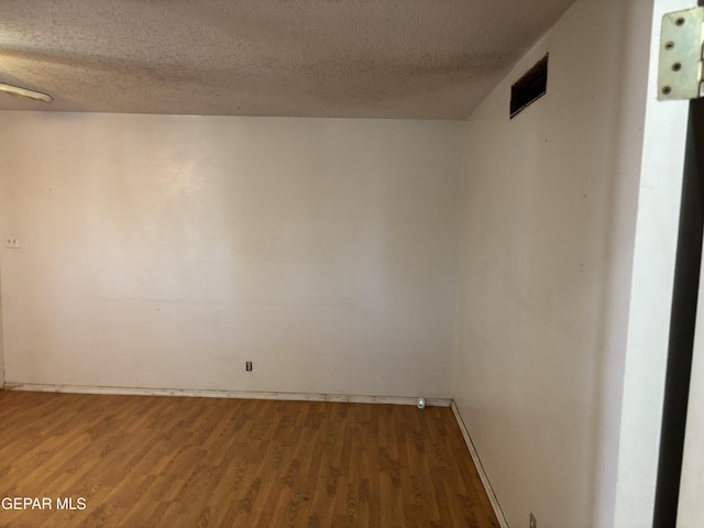 spare room featuring a textured ceiling and wood finished floors