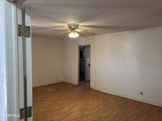 unfurnished room with ceiling fan, wood finished floors, baseboards, and a textured ceiling