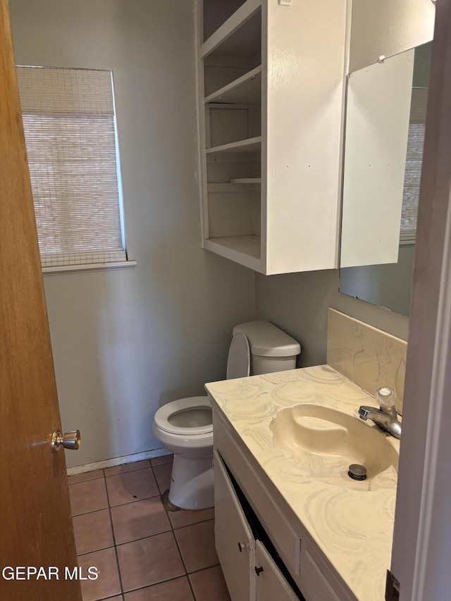 half bathroom featuring tile patterned flooring, toilet, and vanity