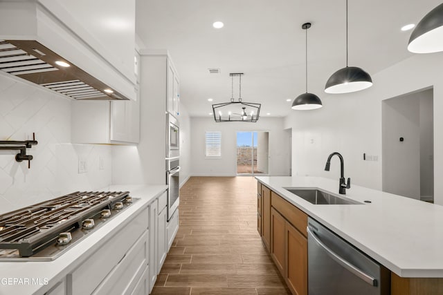 kitchen featuring premium range hood, a sink, backsplash, appliances with stainless steel finishes, and light countertops