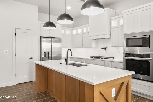 kitchen featuring appliances with stainless steel finishes, white cabinetry, wood tiled floor, and a sink