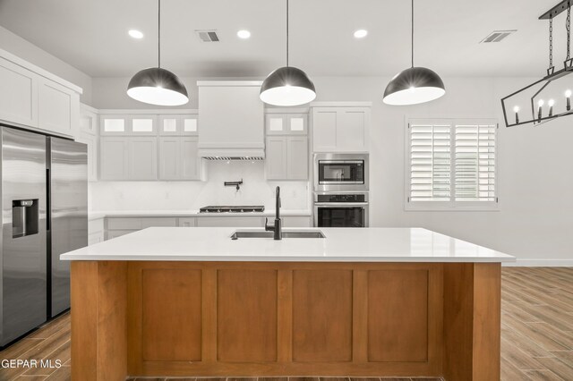 kitchen with visible vents, custom range hood, a sink, stainless steel appliances, and light wood-style floors