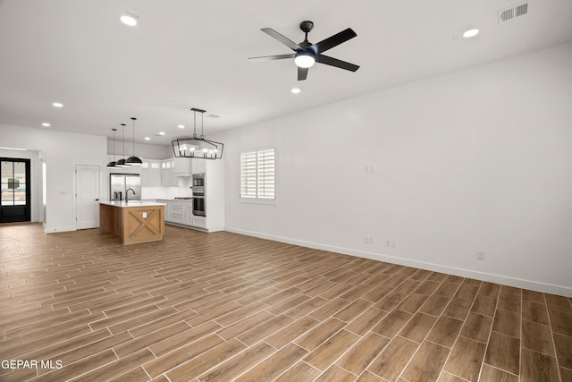 kitchen with light wood finished floors, visible vents, open floor plan, light countertops, and a sink