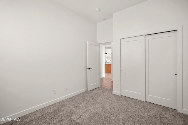 unfurnished bedroom featuring a closet, baseboards, and carpet flooring