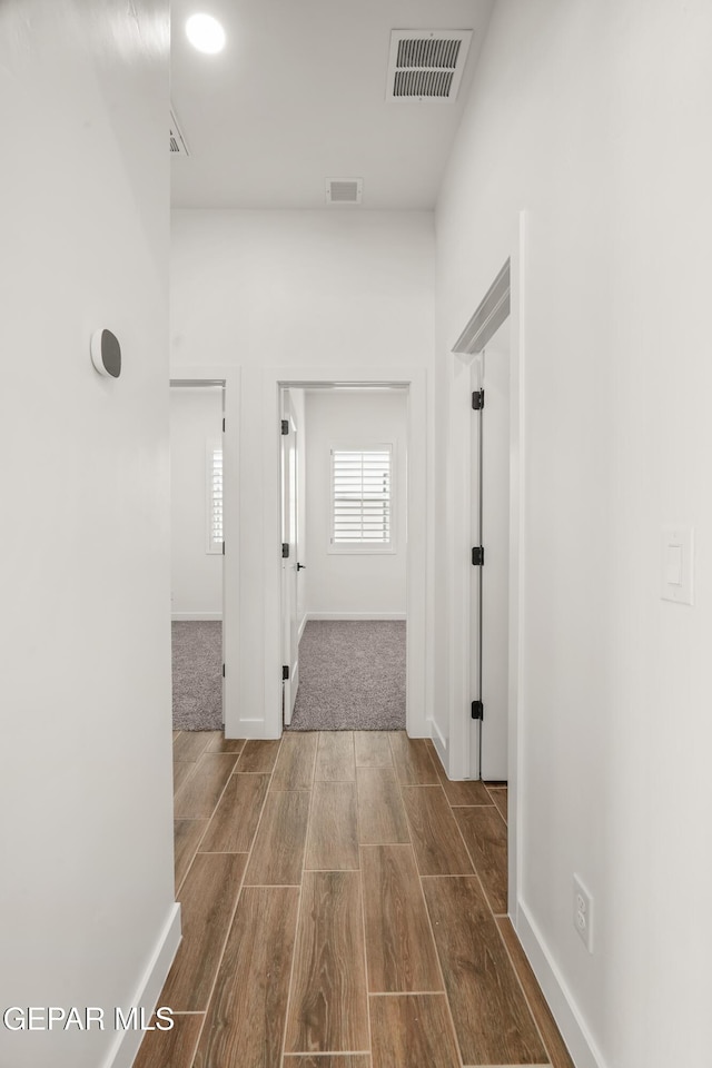 corridor featuring visible vents, baseboards, and wood tiled floor