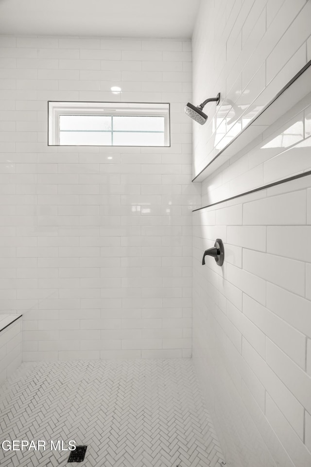 full bath featuring tiled shower and a healthy amount of sunlight