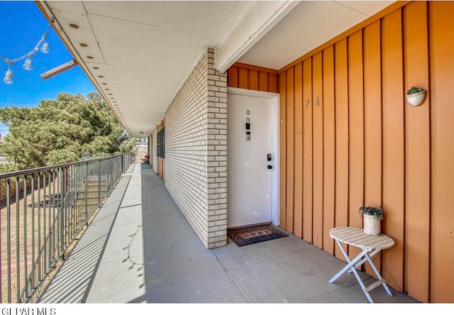 entrance to property featuring brick siding, board and batten siding, and a balcony