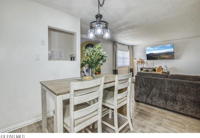 dining room with baseboards, a textured ceiling, and wood finished floors