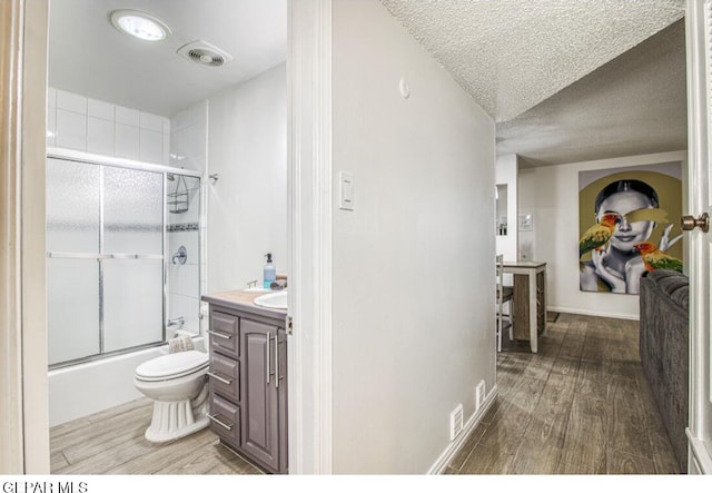 full bath featuring combined bath / shower with glass door, a textured ceiling, wood finished floors, and toilet