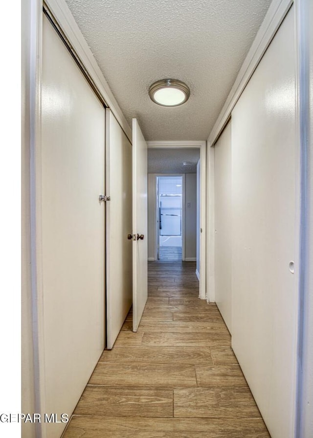 hall with light wood-style flooring and a textured ceiling