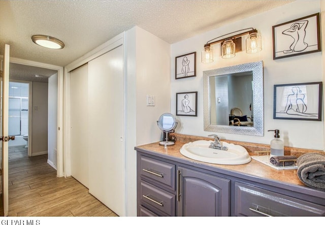 bathroom featuring vanity, wood finished floors, and a textured ceiling