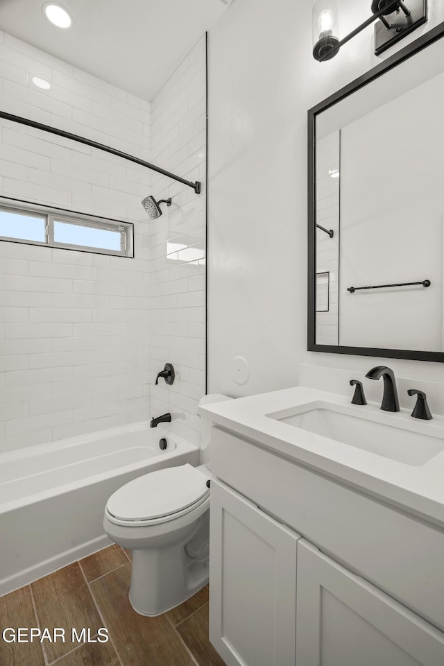 bathroom with toilet, vanity,  shower combination, and wood tiled floor