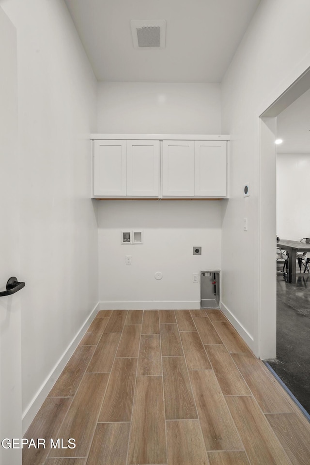 laundry room featuring hookup for a washing machine, wood finished floors, hookup for an electric dryer, cabinet space, and hookup for a gas dryer