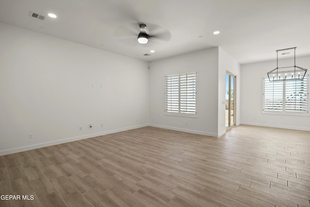 unfurnished room featuring ceiling fan with notable chandelier, recessed lighting, light wood-style floors, and visible vents