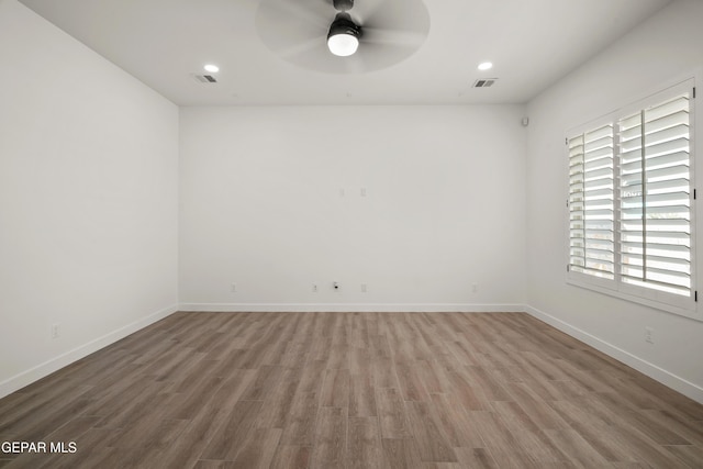 spare room featuring visible vents, baseboards, and wood finished floors