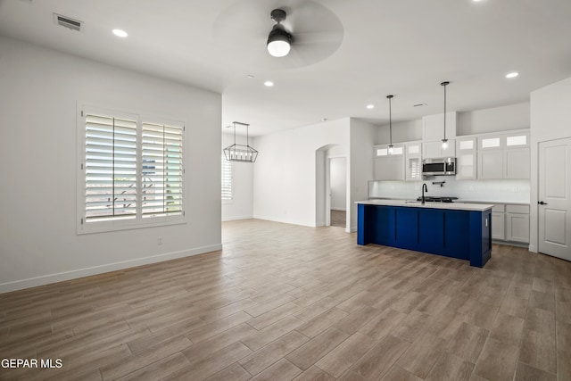 kitchen featuring visible vents, arched walkways, a sink, light countertops, and stainless steel microwave