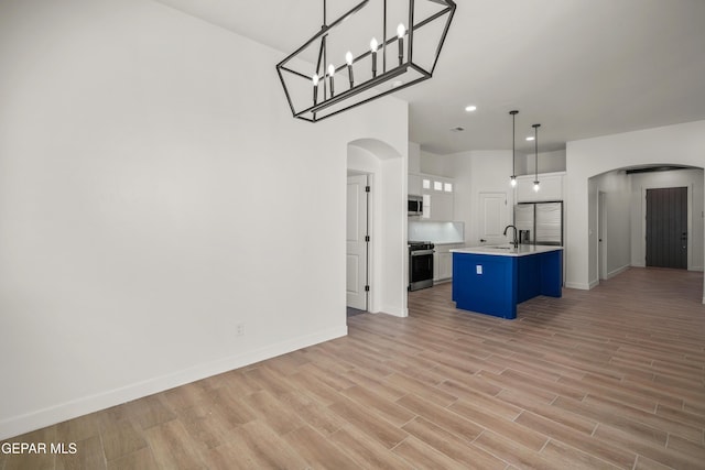 kitchen featuring arched walkways, open floor plan, white cabinets, and stainless steel appliances