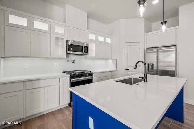 kitchen with backsplash, wood tiled floor, light countertops, stainless steel appliances, and a sink