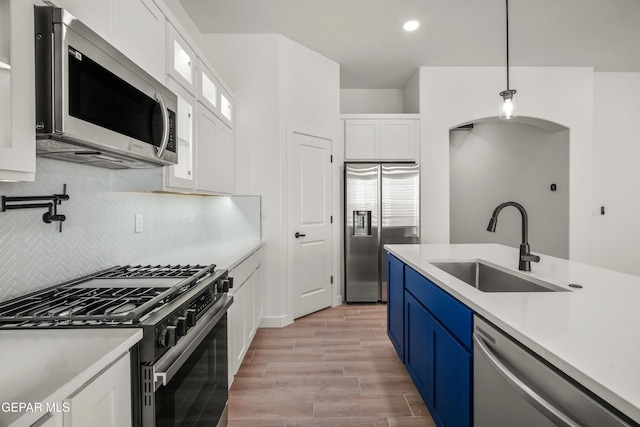 kitchen featuring a sink, stainless steel appliances, light countertops, white cabinets, and blue cabinets