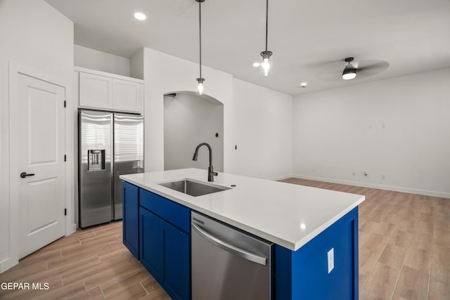 kitchen featuring blue cabinetry, wood finish floors, light countertops, appliances with stainless steel finishes, and a sink