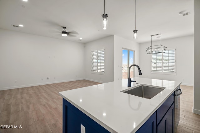 kitchen with light countertops, blue cabinetry, visible vents, and a sink