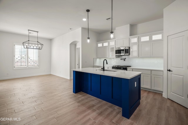 kitchen with a sink, stainless steel microwave, tasteful backsplash, arched walkways, and stove