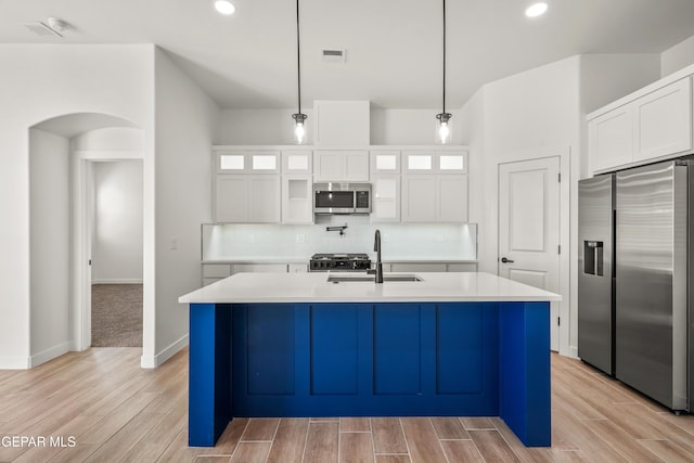 kitchen featuring visible vents, a sink, backsplash, stainless steel appliances, and arched walkways